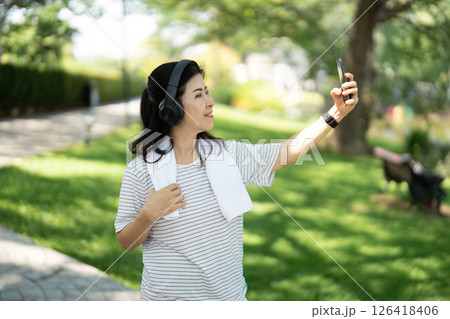 Wellness and joy: Elderly woman taking a selfie while walking Wellness and joy: Elderly woman taking a selfie while walking 126418406