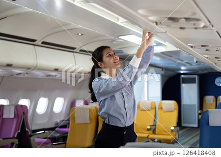 Business travel: Flight attendant adjusting overhead compartment 126418408