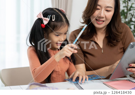 Mother and Daughter Back to School. Joyful learning experience as mother guides daughter with tablet. 126418430