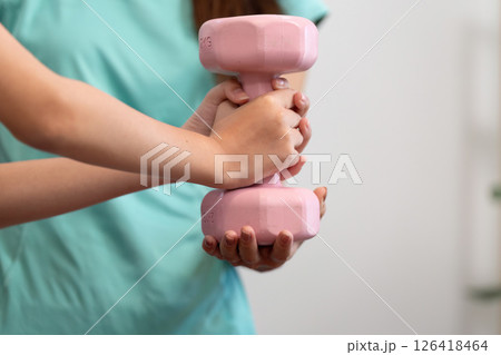 Hands holding pink dumbbell during mother daughter workout Hands holding pink dumbbell during mother daughter workout 126418464