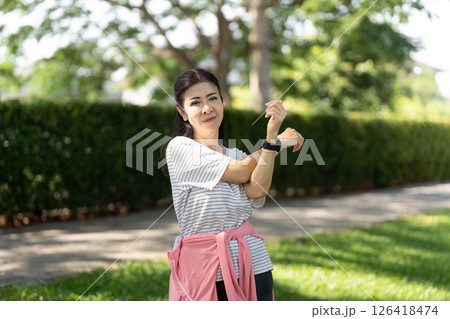 Wellness through yoga stretching for elderly woman in green park 126418474