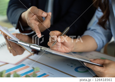 Analyzing Financial Reports. Professionals discussing strategy over charts and documents. Analyzing Financial Reports. Professionals discussing strategy over charts and documents. 126418561