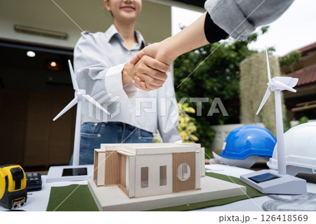 Sustainability engineers shaking hands over architectural design Sustainability engineers shaking hands over architectural design 126418569