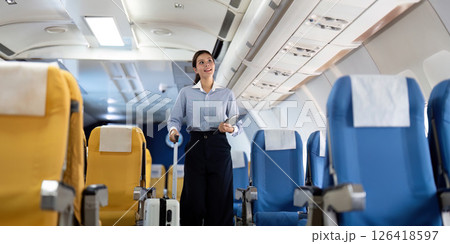 Business travel: Asian woman walking in airplane aisle with suitcase 126418597