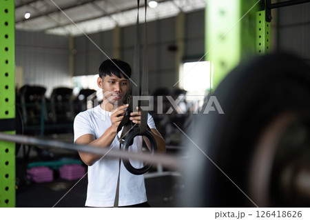 Wellness through Fitness. Young man preparing for workout on gym rings. Wellness through Fitness. Young man preparing for workout on gym rings. 126418626