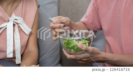 Wellness and Togetherness. Elderly couple feeding each other healthy salad at home. Wellness and Togetherness. Elderly couple feeding each other healthy salad at home. 126418719