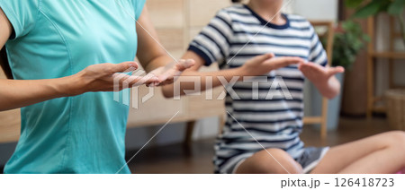 Wellness routine of mother and daughter practicing mindful yoga 126418723