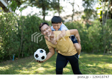 Activity: Father Carrying Son on His Back While Playing Soccer Activity: Father Carrying Son on His Back While Playing Soccer 126418747