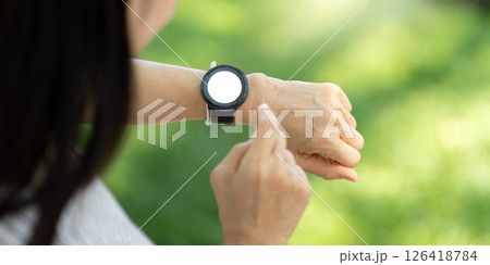 Wellness engagement with elderly woman using fitness watch in nature 126418784