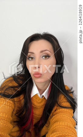 Charming Brunette Woman in Yellow Sweater Pouting Playfully for the Camera Charming Brunette Woman in Yellow Sweater Pouting Playfully for the Camera 126418919