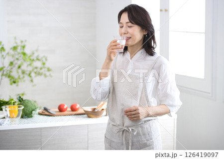 キッチンで水を飲む笑顔のミドル女性 キッチンで水を飲む笑顔のミドル女性 126419097