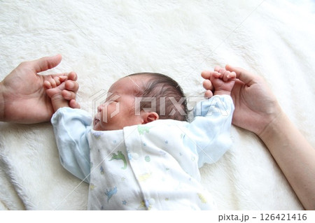 パパとママの手に両手を乗せて眠る新生児 126421416