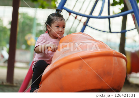 happy toddler girl riding jet ski toy at playground 126421531
