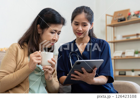 Caregiver showing health information on a tablet to an elderly patient 126423108