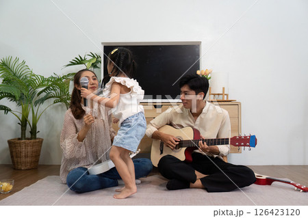 Musical Moments and Family Joy. A daughter interacting with her parents during a musical session. Musical Moments and Family Joy. A daughter interacting with her parents during a musical session. 126423120