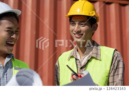 Engaged Engineers. Engineers laughing and reviewing plans at a logistics site. 126423163