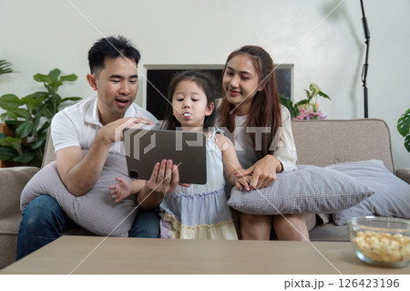 Family sharing a fun moment while watching a tablet, showcasing engagement and joy. Family sharing a fun moment while watching a tablet, showcasing engagement and joy. 126423196