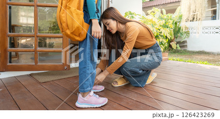 Prepping for School. A mother tying her daughter shoelaces before school. Prepping for School. A mother tying her daughter shoelaces before school. 126423269