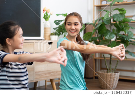 Mother and daughter wellness exercise routine at home 126423337