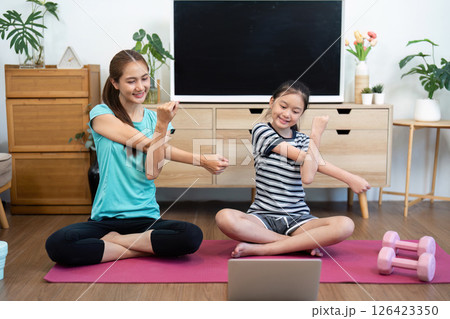 Wellness yoga warm-up for mother and daughter practicing together 126423350