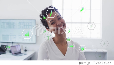 Image of ecology icons over biracial businesswoman smiling in office 126425027