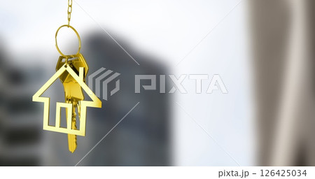 Golden house keychain image over blurred cityscape background 126425034