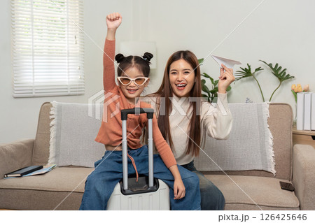 Celebrating Travel Dreams Together. A mother and daughter share their excitement for an upcoming trip while showing off paper crafts. Celebrating Travel Dreams Together. A mother and daughter share their excitement for an upcoming trip while showing off paper crafts. 126425646