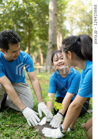 Family volunteers planting a young tree together to support environmental sustainability 126425668