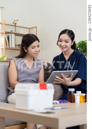 Caregiver discussing health information with elderly client using a tablet during home consultation 126425691