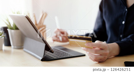 Close up hand of woman holding credit card and using laptop computer at home. Online shopping concept 126426251