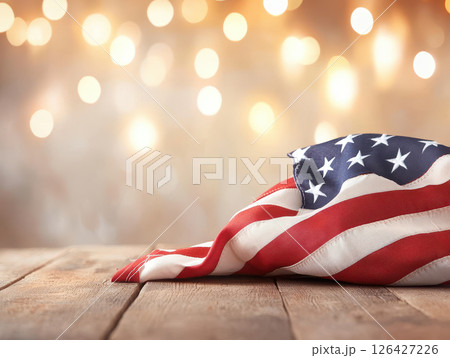 American flag draped on wooden table with bokeh background, evoking patriotism and celebration 126427226