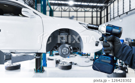 Mechanic uses a impact wrench cordless in service garage 126428302