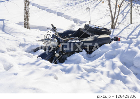An old motorcycle with a sidecar sank into a snowdrift in winter An old motorcycle with a sidecar sank into a snowdrift in winter 126428836
