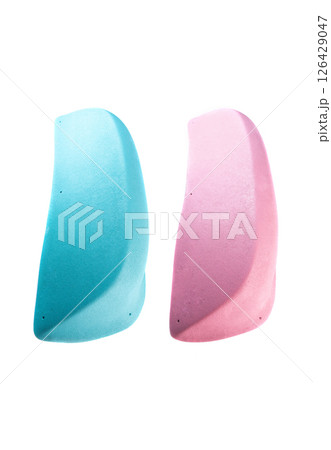 Two elongated climbing holds with smooth rounded edges in blue and pink colors vertically arranged on white background. Ideal for catalog or shop display. 126429047