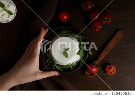 Ricotta in a bowl with tomatoes on a dark background 126430636