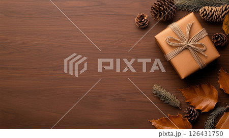 beautifully wrapped handmade gift box sits on wooden surface, surrounded by pine cones and autumn leaves, creating warm and inviting atmosphere 126431750