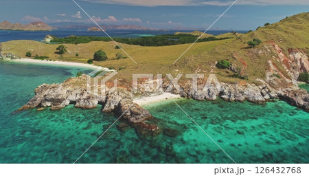 Aerial view of crystal-clear turquoise water gently washing against the rocky coastline of a picturesque island in Komodo National Park, Indonesia, showcasing the raw beauty of nature 126432768