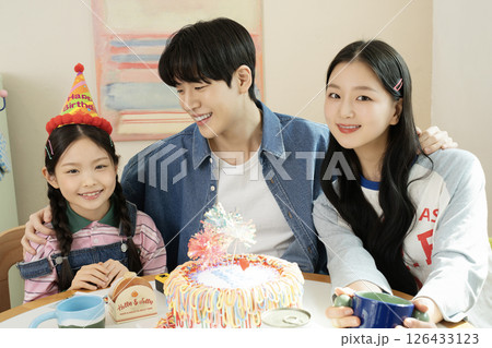A family preparing a delicious cake for their daughter's birthday A family preparing a delicious cake for their daughter's birthday 126433123