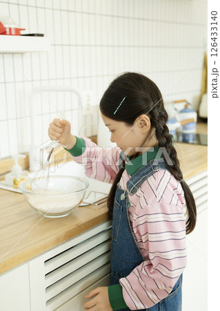A child whipping bubbles with a whisk 126433140