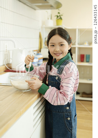 A child whipping bubbles with a whisk A child whipping bubbles with a whisk 126433145