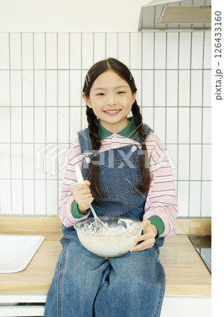 Child sitting on the sink and whipping bubbles with a whisk 126433160