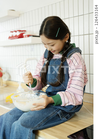 Child sitting on the sink and whipping bubbles with a whisk Child sitting on the sink and whipping bubbles with a whisk 126433164