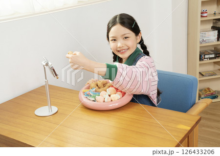 A cute child YouTuber who stands up on his smartphone and films a mukbang A cute child YouTuber who stands up on his smartphone and films a mukbang 126433206