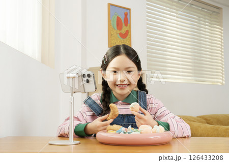 A cute child YouTuber who stands up on his smartphone and films a mukbang 126433208
