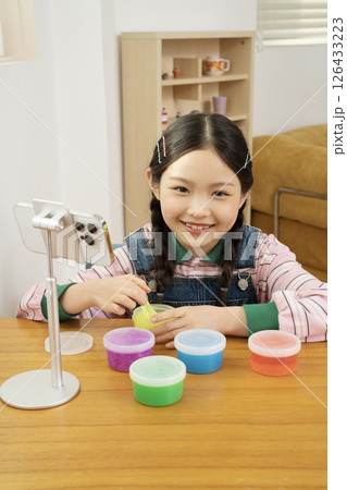 A cute child YouTuber who puts his smartphone upright and takes pictures while playing with slime. 126433223