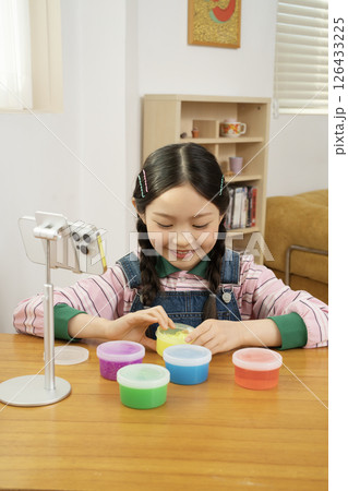 A cute child YouTuber who puts his smartphone upright and takes pictures while playing with slime. 126433225