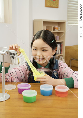 A cute child YouTuber who puts his smartphone upright and takes pictures while playing with slime. 126433227