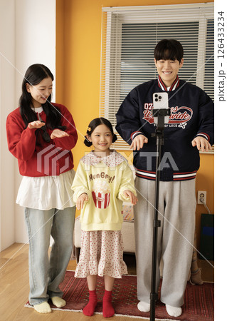 The MZ family filming a short-form challenge with a mobile phone tripod set up. 126433234