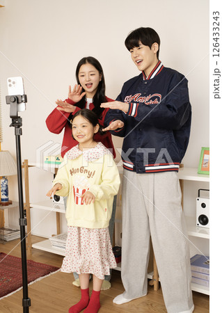 The MZ family filming a short-form challenge with a mobile phone tripod set up. 126433243