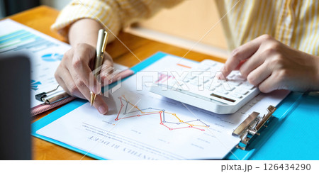 Close up Business woman using calculator and laptop for do math finance on wooden desk in office and business working background, tax, accounting, statistics and analytic research concept 126434290